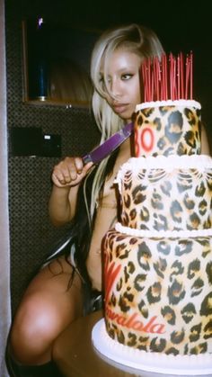 a woman sitting in front of a three tiered cake with leopard print on it