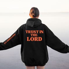 Everyone deserves a cozy go-to Christian hoodie to curl up in, so go for one that's soft, smooth, and stylish.  This cool Christian hoodie with a design on the back and Proverbs 3:5 Bible Verse on the left sleeve is perfect for cooler evenings or chilly days! Whether you are spending a lazy day on the couch or want a comfy style and casual look, this cute Trust in the Lord hoodie will keep you warm and comfy.  It's a stylish way to show off your faith and share encouraging faith-based messages f Inspirational Long Sleeve Hoodie For Fall, Inspirational Letter Print Hoodie For Fall, Inspirational Graphic Print Hoodie For Fall, Inspirational Hoodie Sweatshirt For Fall, Inspirational Hoodie For Fall Streetwear, Inspirational Fall Streetwear Hoodie, Inspirational Hooded Sweatshirt For Fall, Inspirational Winter Streetwear Sweatshirt, Inspirational Long Sleeve Relaxed Fit Hoodie