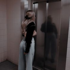 a woman standing in front of an elevator with her back turned to the camera,