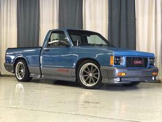 a blue pick up truck parked in front of a curtain