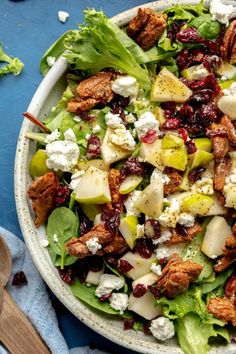 a salad in a bowl with apples, cranberries and pecans on the side