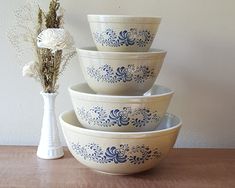 four bowls stacked on top of each other next to a vase with flowers in it