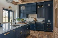 a large kitchen with blue cabinets and wood flooring, along with an island in the middle