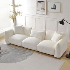 a white couch sitting on top of a hard wood floor next to a lamp and rug