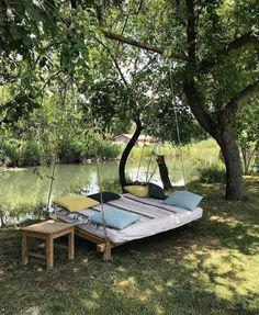 a hammock is set up next to a river with two benches on it