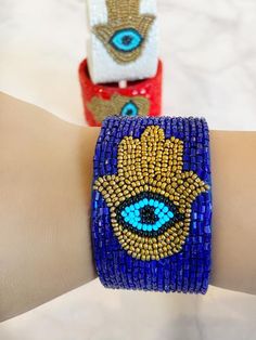 All the vibes you need to keep the evil away in one bracelet. A intricate Hamsa and a bold evil eye design crafted into a luxurious chic  bracelet.  Always protected!! Timeless enough to be worn with any outfit. Slides on and off with an open cuff flexible enough to fit everyone.Comes in sleek FRESHALAMODE packaging making it perfect for gifting. A hamsa prayer card is included as well. Choose between 3 rich colors. RedWhite Blue Symbolic Evil Eye Beaded Bracelets Gift, Evil Eye Cuff Bracelet, Handmade Multicolor Spiritual Evil Eye Bracelet, Hamsa Prayer, Adjustable Hand-strung Evil Eye Bracelet For Festival, Bohemian Blue Evil Eye Bracelet Hand-strung, Hair Brush Set, Free Tv, Eye Gift