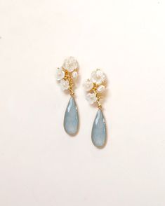 a pair of earrings with flowers and pearls on the end of each earring, sitting on a white surface