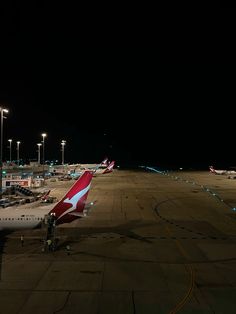 several airplanes parked on the tarmac at an airport with their lights turned on in the dark