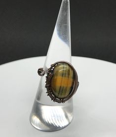 Blue and Yellow Tiger Eye RIng in Copper. adjustable size. Coated with Protectaclear. ProtectaClear is a clear, protective coating that is easy to apply but is tough enough to protect jewelry and is safe for wear against skin. ProtectaClear is practically invisible once applied, dries quickly and will seal and protect jewelry from tarnish, oxidation, and corrosion Adjustable Handmade Clear Ring, Adjustable Round Clear Jewelry, Handmade Adjustable Clear Jewelry, Adjustable Clear Jewelry, Unique Adjustable Clear Jewelry, Tiger Ring, Tiger Eye Ring, Eye Ring, Blue And Yellow