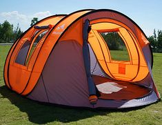 an orange and gray tent sitting on top of a lush green field