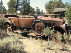 an old rusted out truck sitting in the middle of nowhere