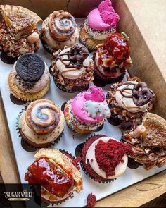 a box filled with lots of different flavored cupcakes