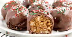 chocolate covered candy balls on a plate with sprinkles and christmas decorations around them