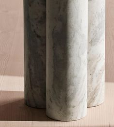 three white marble vases sitting on top of a wooden table next to each other