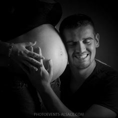 a black and white photo of a man holding his pregnant belly