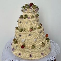 a three tiered wedding cake with strawberries and flowers on the top is sitting on a lace doily