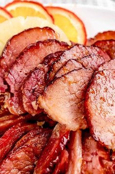 sliced meat and orange slices on a white plate