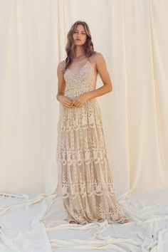 a woman standing in front of a white backdrop wearing a dress with an open back