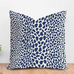 a blue and white leopard print pillow sitting on top of a wooden floor next to a potted plant