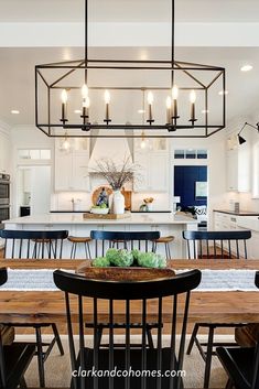 an open kitchen and dining room area with wooden table, chairs, and chandelier