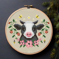 a cross stitch pattern with a cow and flowers