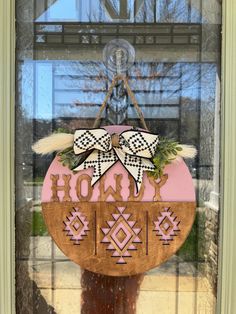 a wooden sign hanging from the side of a door with a bow on it's head