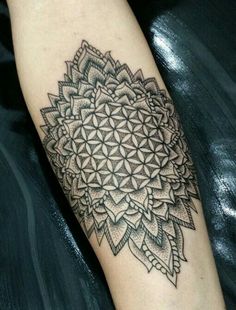 a black and white photo of a flower of life tattoo on the left arm with an intricate design