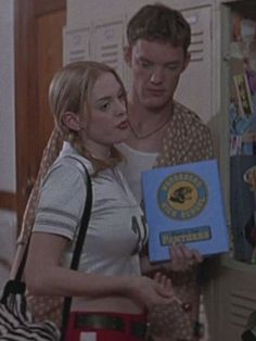 a man and woman standing next to each other in a room with lockers on the wall