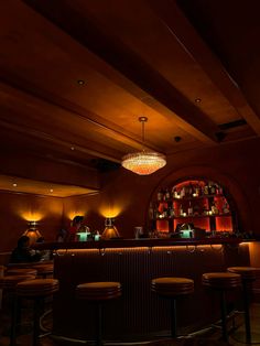 a dimly lit bar with several stools and lights on the wall in front of it