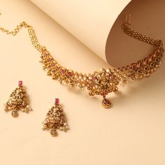 Description Inspired by your love for temple jewelry this antique cz choker set showcases the intricate craft of carving Goddess Lakshmi along with filigree patterns. This elegant choker has an antique gold finish, kempu stone, and cluster pearl drops for dressing up your ethnics. Details & Specifications: Materials used: CZ stones with Antique Gold Plating Weight - Necklace: 53.8 gms, Earrings: 17.35 gms Length - Necklace: 21 cms, Earrings: 4.5 cms Make it custom Want to make it a custom choker Antique Choker, Luxury Closets, Closets Design, Unique Gold Jewelry Designs, Temple Jewelry Necklace, Elegant Choker, Antique Necklaces Design, Jewellery Business, Pretty Jewelry Necklaces