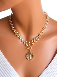 "This a a beautiful triple layer pearl necklace with a large Mary pendant hanging from toggle front. These lovely layers are made of 6mm freshwater pearls on 24k gold-plated brass with a 18k gold filled Mother Mary pendant, measuring 25mm, hanging form the gold filled toggle. This necklace can be worn many ways as shown in photos. Comes in a 50\" length. All my jewelry comes in a cute gift box with jewelry care instructions. If you would like this style necklace made with a gemstone, please send Cheap Gold Necklaces With Large Beads, Gold Double Strand Pearl Necklace, Gold Multi-strand Pearl Charm Necklace, Gold Double Strand Pearl Necklace For Jewelry Making, Gigi 2023, Pearl And Gold Necklace, Necklace Women Gold, Baroque Necklace, 14kt Gold Jewelry