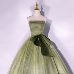 a dress on a mannequin with a green bow