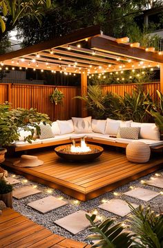 an outdoor living area with wooden decking and lights strung over the fire pit, surrounded by potted plants