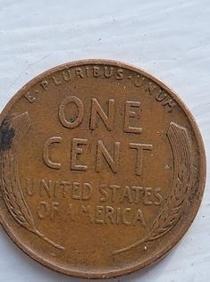 an old one cent united states of america coin on a white tablecloth with the words, one cent united states of america printed on it