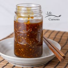 a glass jar filled with food sitting on top of a plate next to chopsticks