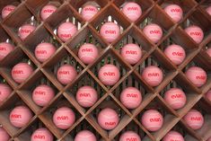 many pink tennis balls are arranged on a wooden rack