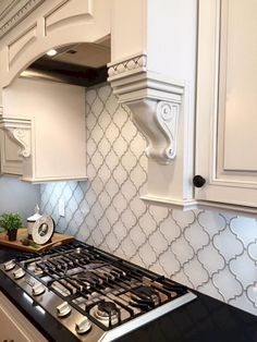 a stove top oven sitting inside of a kitchen next to white cabinets and counter tops