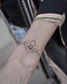 a woman's arm with a small flower tattoo on the left side of her wrist