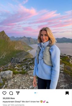 a woman standing on top of a mountain next to the ocean