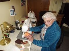 an older woman is using a sewing machine to sew something on the counter top