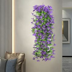 purple flowers are growing up the side of a white wall in a living room,