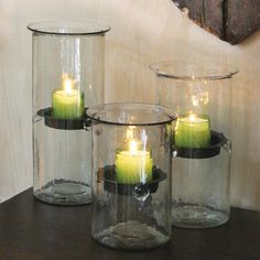 three glass jars with lit candles in them