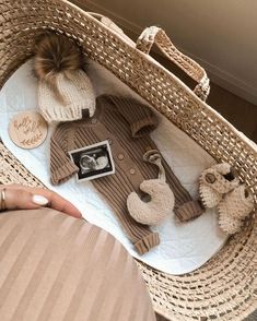 a baby's outfit and booties in a wicker basket on a bed