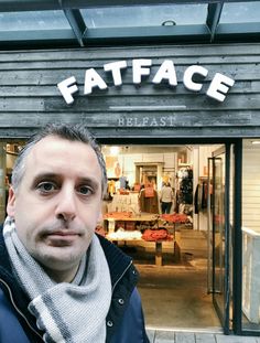 a man standing in front of a store with the words fatface written on it