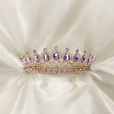 Saya's Tiara features lavender purple colored crystals with clear colored crystal detailing set in gold colored metal.  Max Height: 2.5 Inches  Length End to End: 14.5 Inches  Length of Embellishment: 10.5 Head Opening: 5 Inches  Tiara is adjustable by carefully bending and stretching the ends apart to fit most hair styles and head sizes.  Tiara features loops on each end to secure to hair with bobby pins. Item ships from Michigan, USA. WARNING: CHOKING HAZARD This is not a toy.  This item is not intended for use by children under the age of 5 years old.  There are small pieces that could fall off and create a choking hazard.  All use of this product by any minor, child or dependent should be supervised by an adult 18 years of age or older. Quinceañera Crowns, Quince Crown, Rapunzel Crown, Purple Sweet 16, Sweet 16 Tiara, Lavender Quince, Lavender Purple Color, Quinceanera Crown, Crown Aesthetic