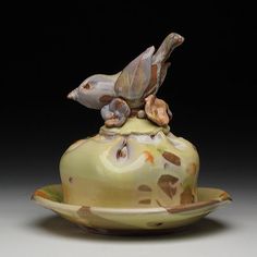 a ceramic bird sitting on top of a saucer