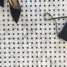 black and white tiled floor with high heeled shoes on the ground next to purse