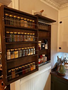 an old wooden spice rack with jars and spices on it's shelves in a kitchen