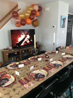 a long table with plates and place settings in front of a television set up for a party