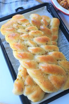 some bread is sitting on a tray next to other food and a bowl with pasta in it